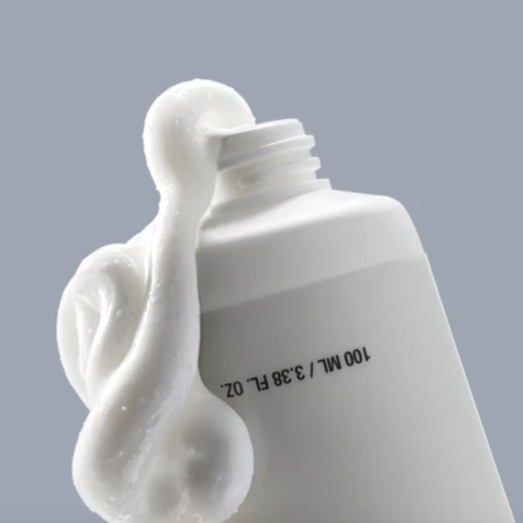 White bottle with a stream of white cream on a gray background