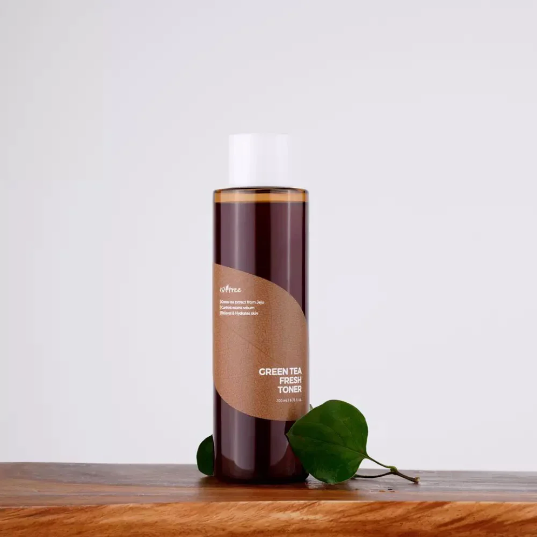 Bottle of green tea fresh toner on a wooden surface with a white background