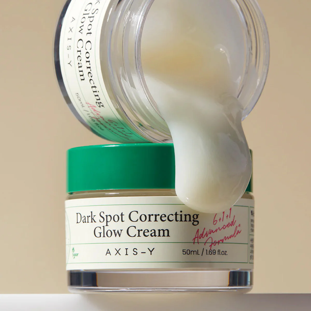 AXIS-Y Dark Spot Correcting Glow Cream being squeezed from a jar onto another jar.