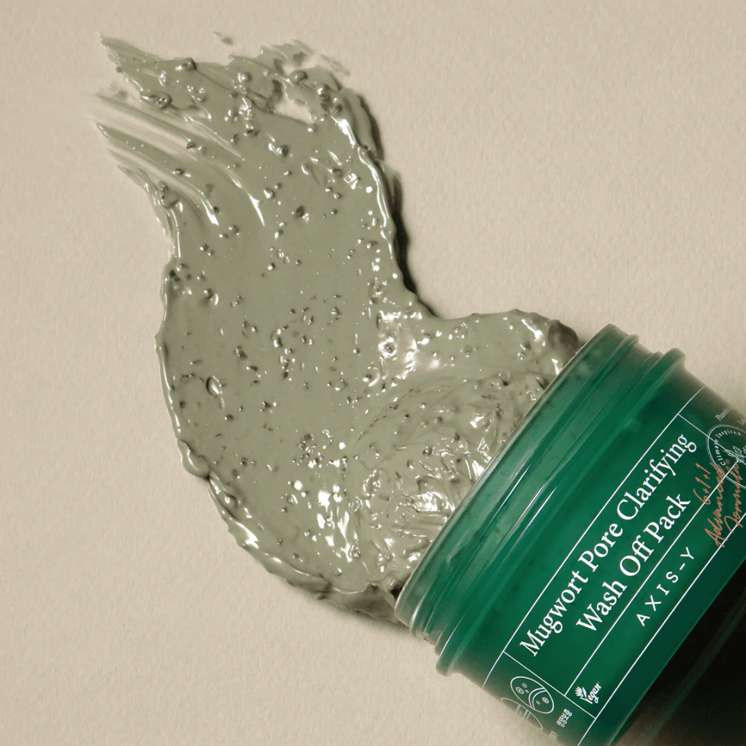 Green jar of Mugwort Pore Clarifying Wash Off Pack with a sample on a beige background