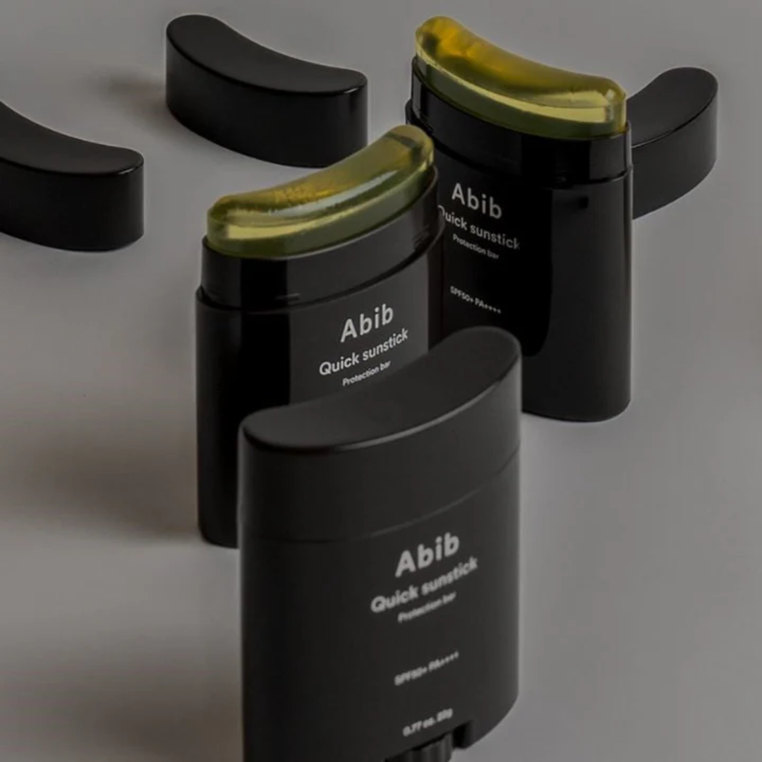 Black sunstick containers with green caps labeled 'Abib' on a gray background