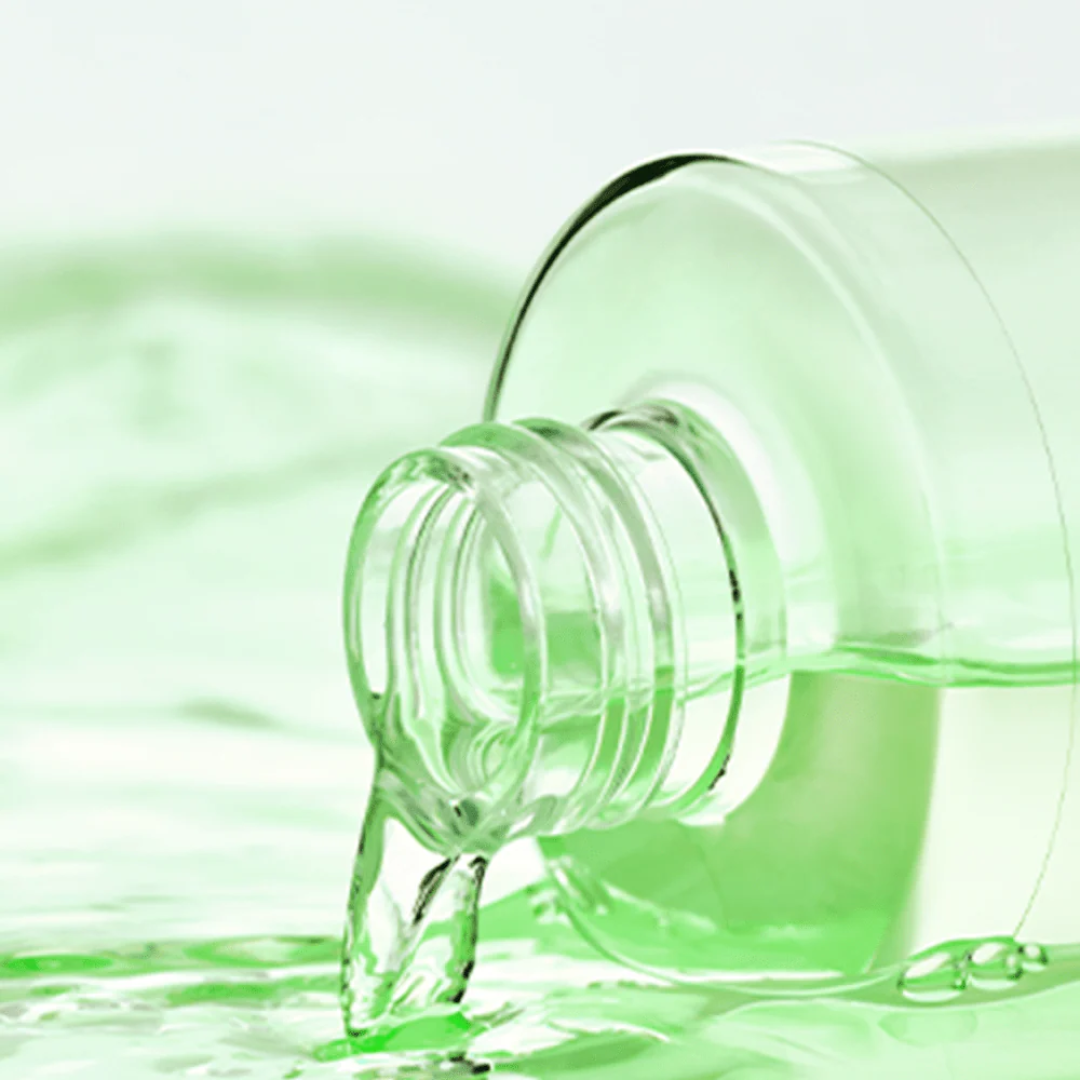 Green liquid being poured from a bottle against a green background