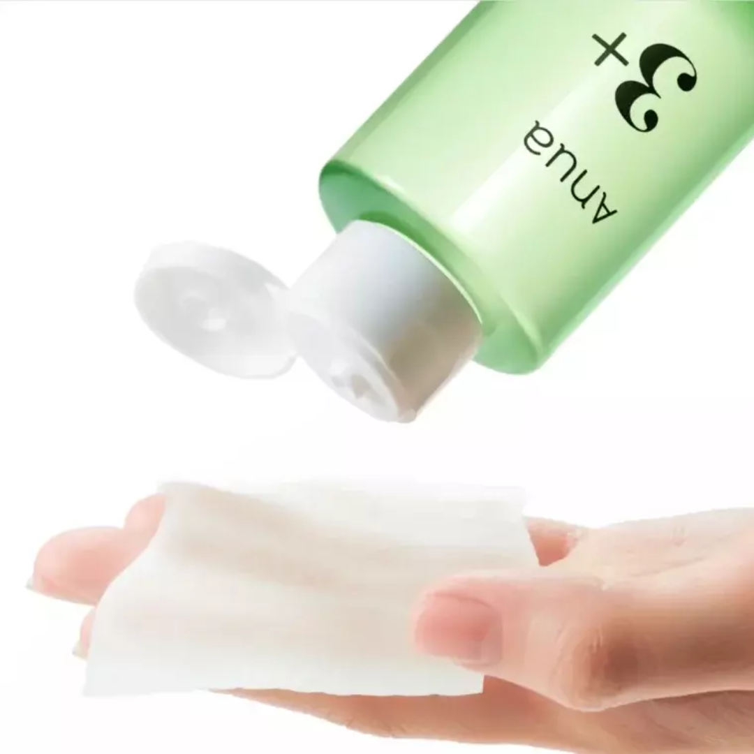 Green bottle of Annua skincare product being applied to a hand on a white background