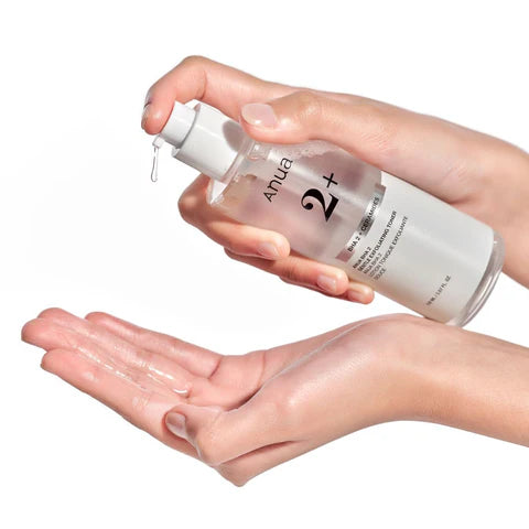 Hand holding a bottle of Ahua skincare product with another hand showing the texture on the palm.