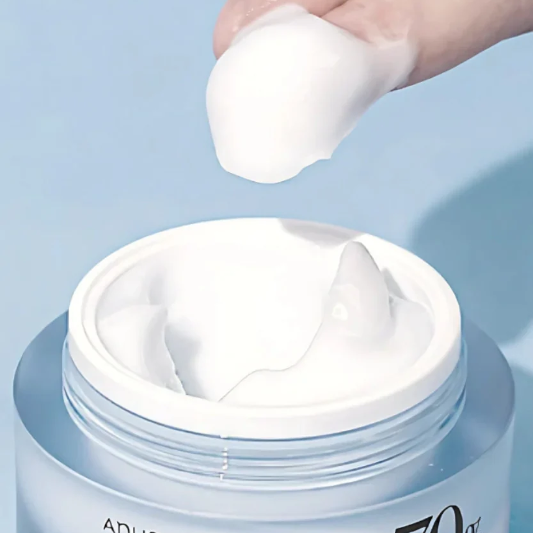 Jar of cream with a hand applying a white cream onto a blue background