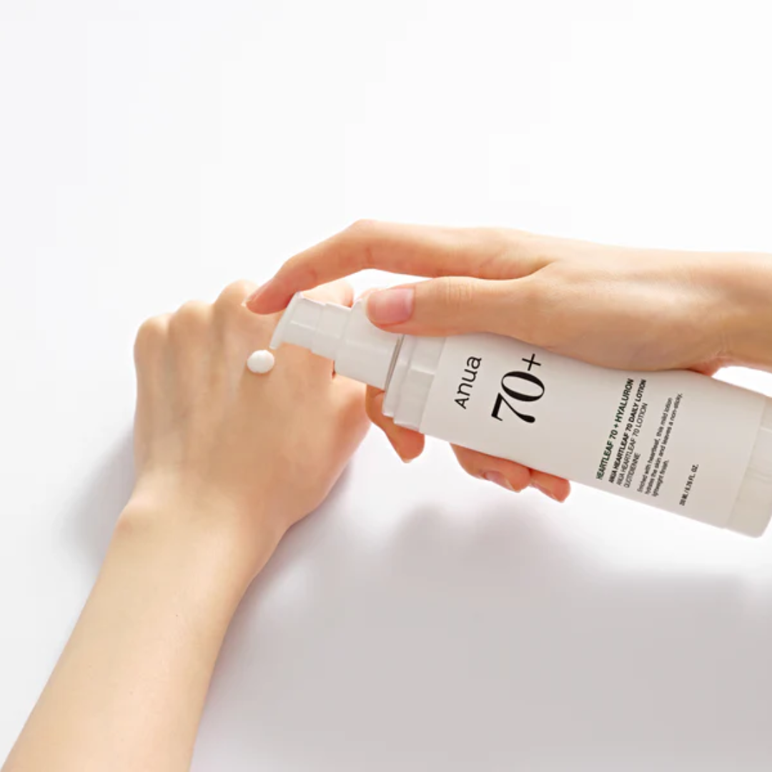 Person applying sunscreen cream to a hand with a white background