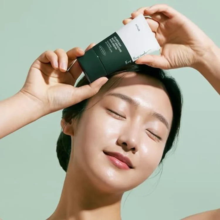 Person applying skincare product to face with a green background