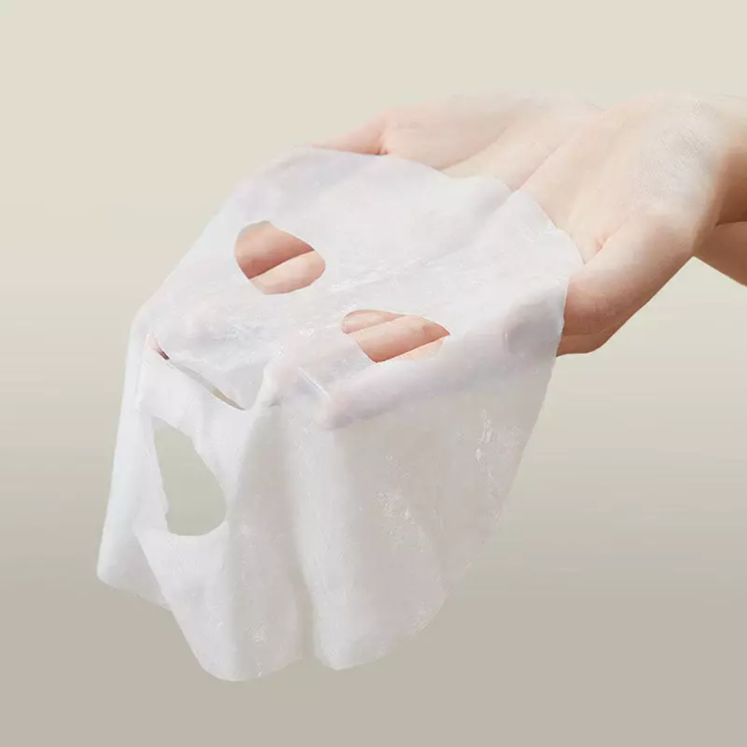 White cotton pad held by a hand against a plain background