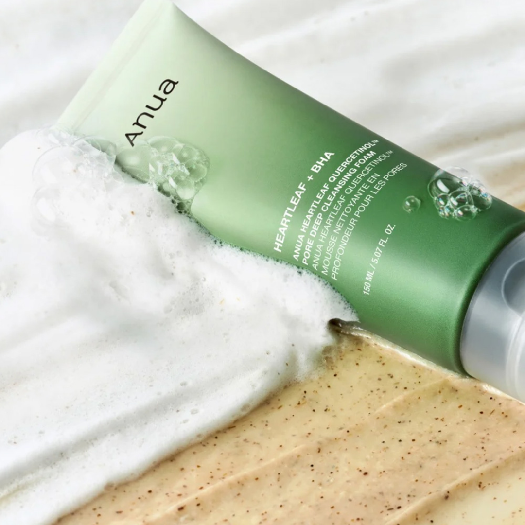 Green skincare product tube labeled 'Anua' with foam on a white background