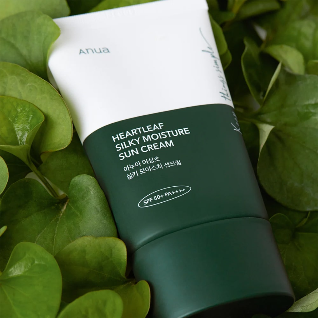 Green sun cream tube labeled 'Heartleaf Silky Moisture Sun Cream' on green leaves
