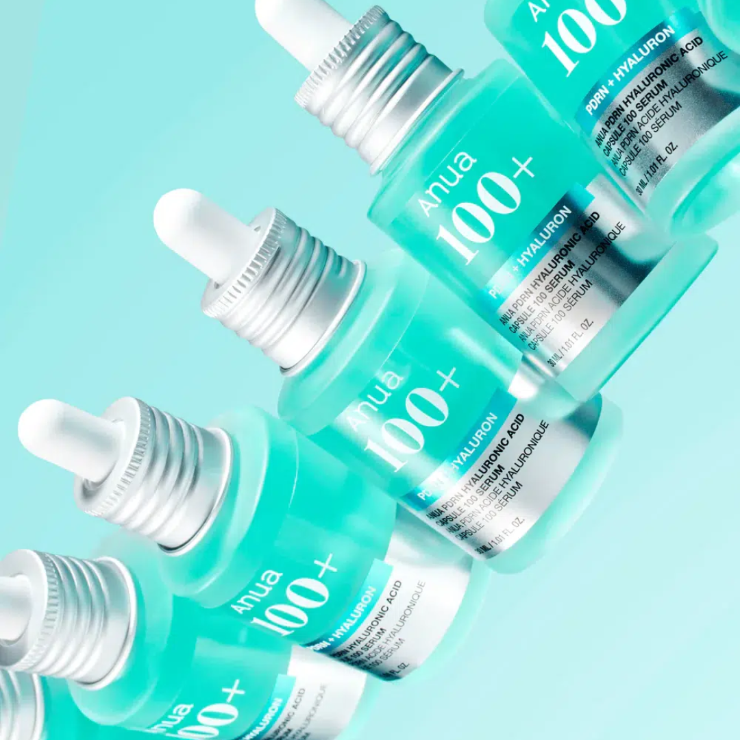 Multiple bottles of Anua 100+ hyaluronic acid serum on a light blue background