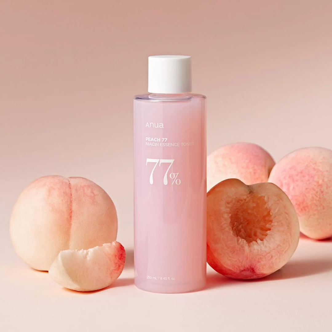 Pink bottle with white cap labeled '77%' surrounded by peaches on a beige background