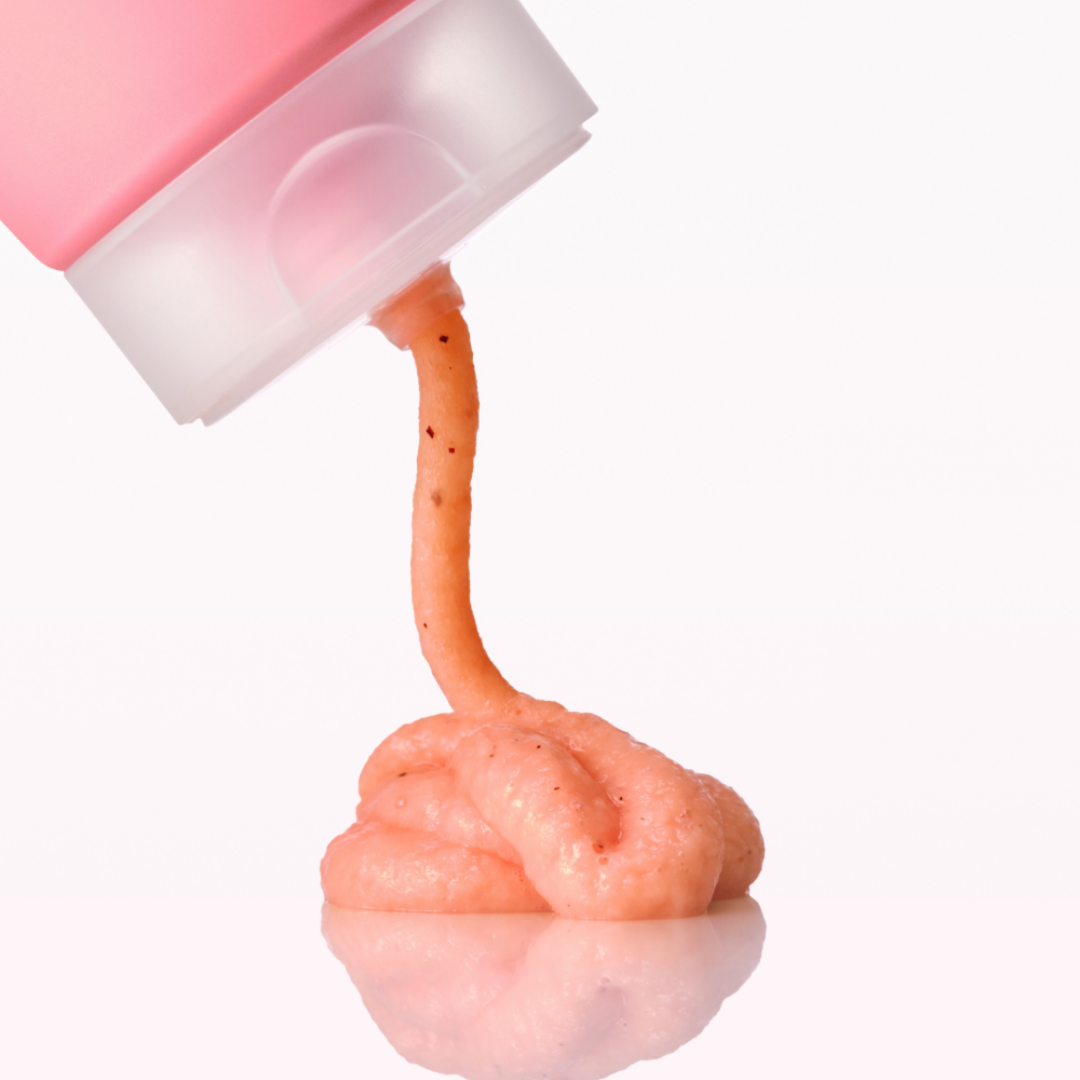 Pink and white container with pink slime being poured out on a white background