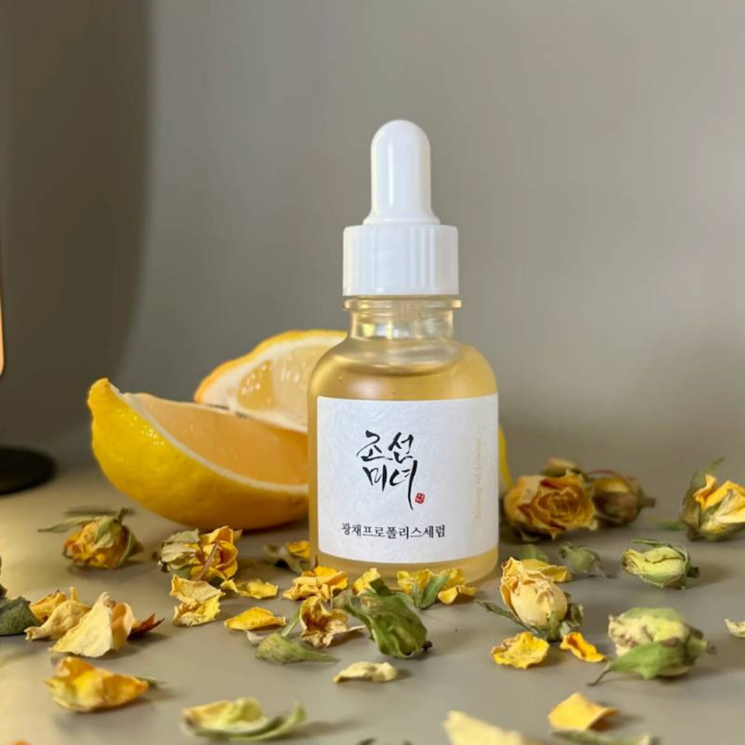 Bottle of skincare serum with dried flowers and lemon slices on a neutral background