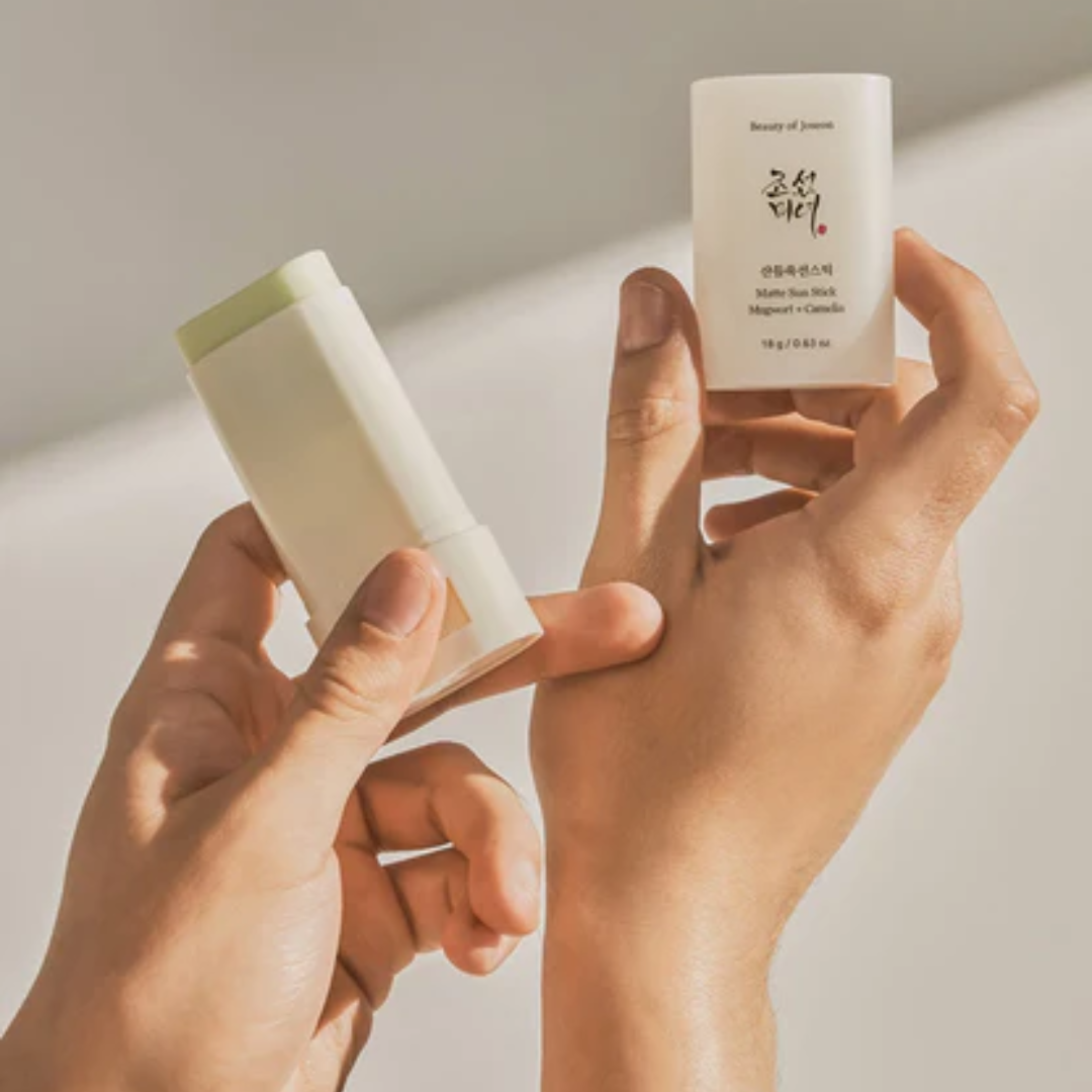 Two hands holding a white stick and a small white container against a light background