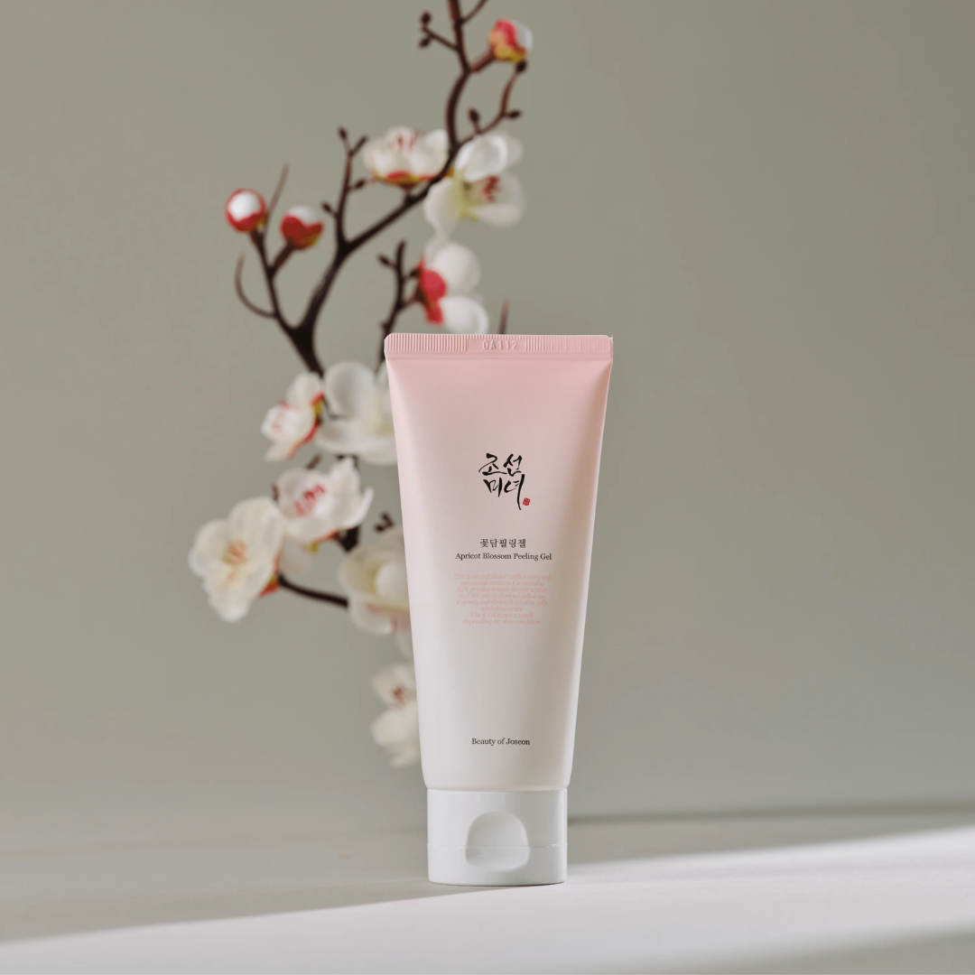 Pink tube of skincare product with cherry blossoms in the background