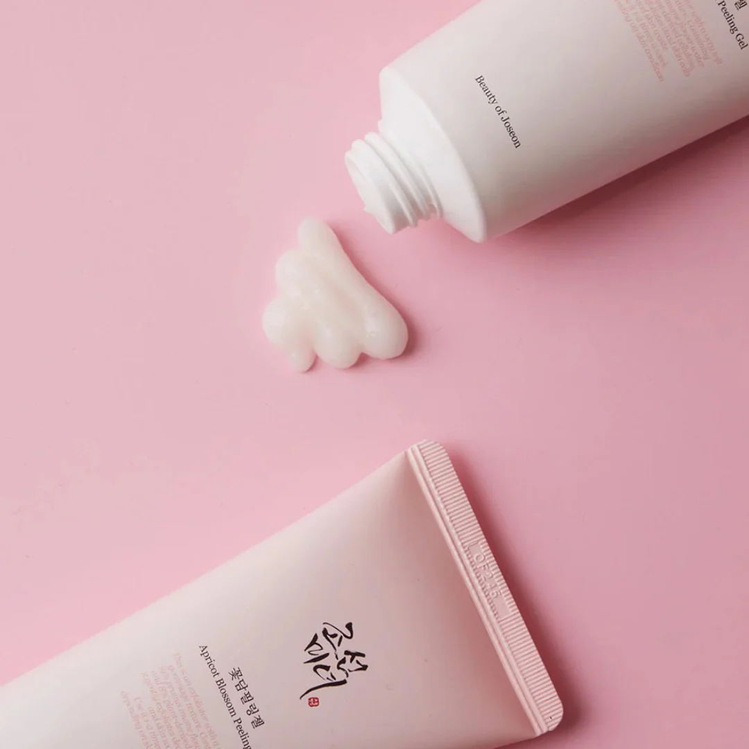 Two tubes of cream on a pink background with one tube open showing cream.