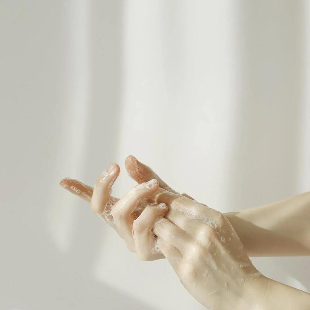 Close-up of hands with soap bubbles against a light background