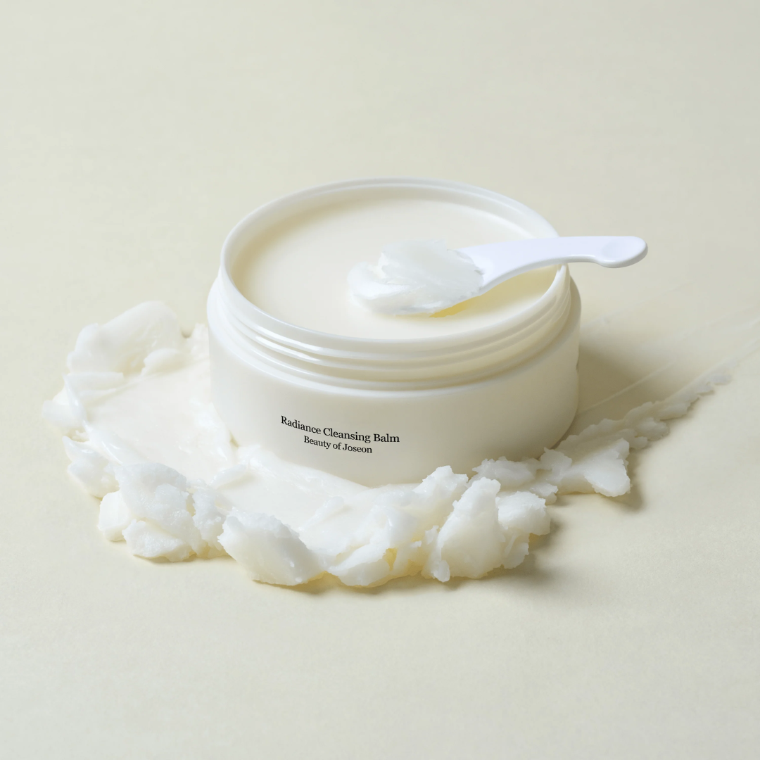 Jar of Radiance Cleansing Balm with a spoon on a light beige background