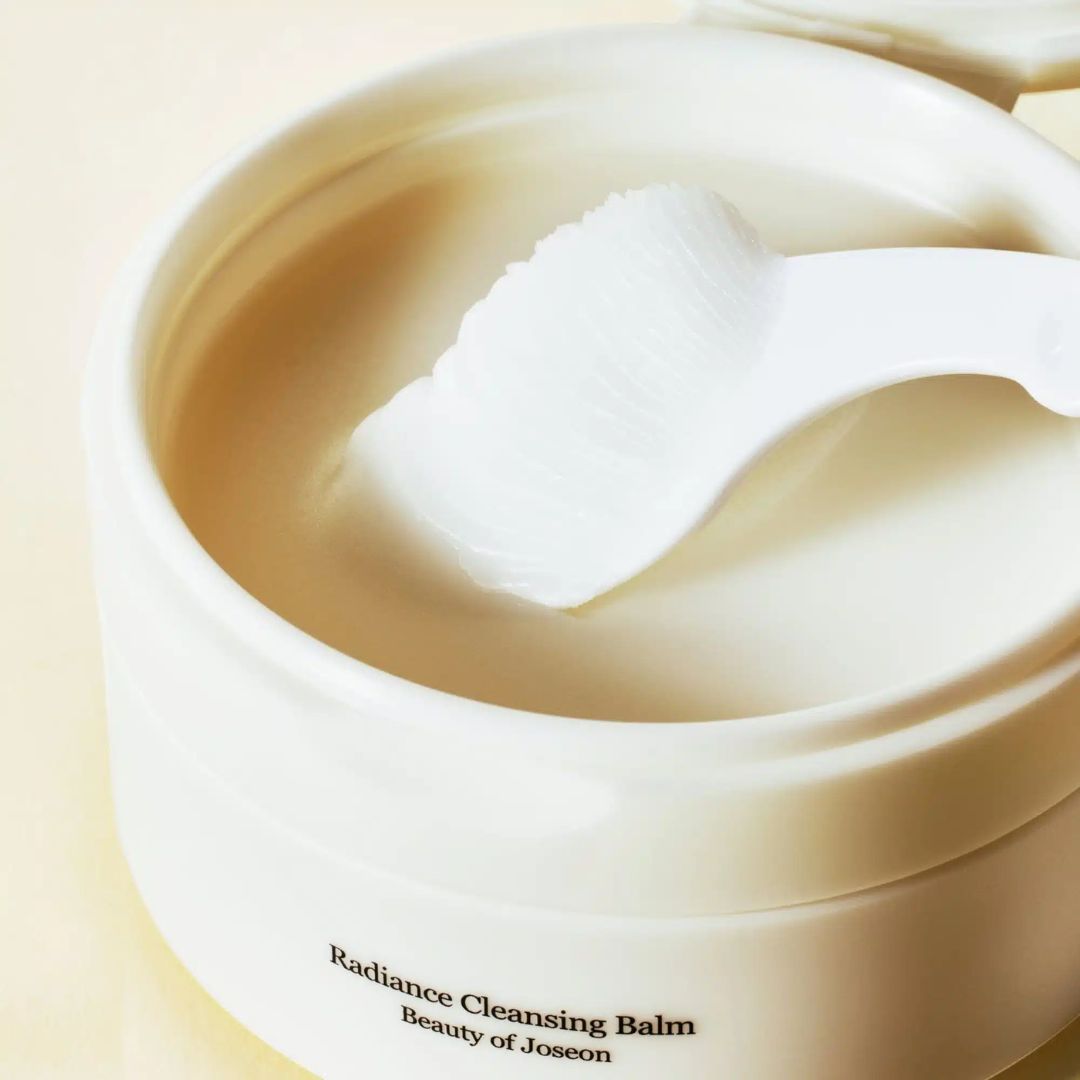 Radiance Cleansing Balm container with a white applicator on a beige background