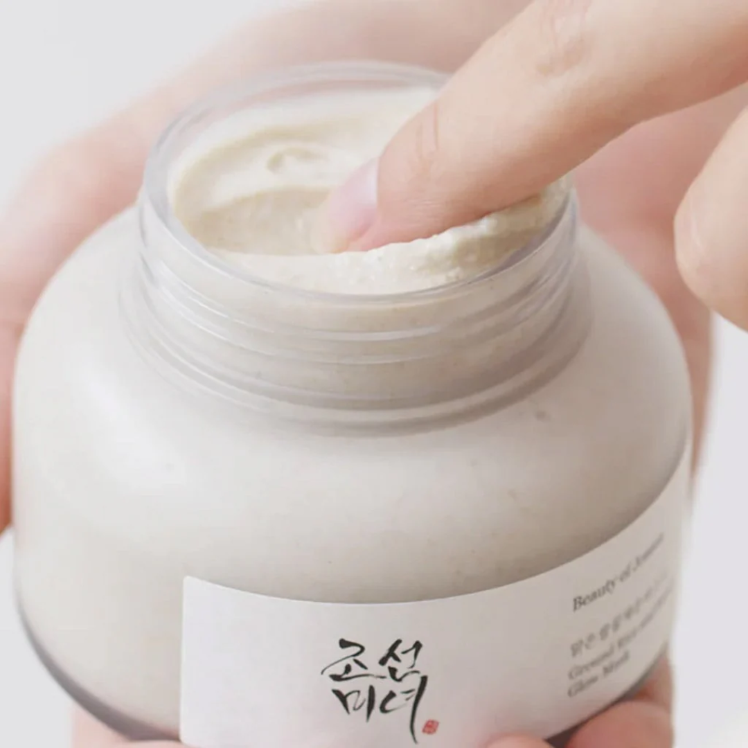 Hand holding a jar of cream with a visible brand label on a light background