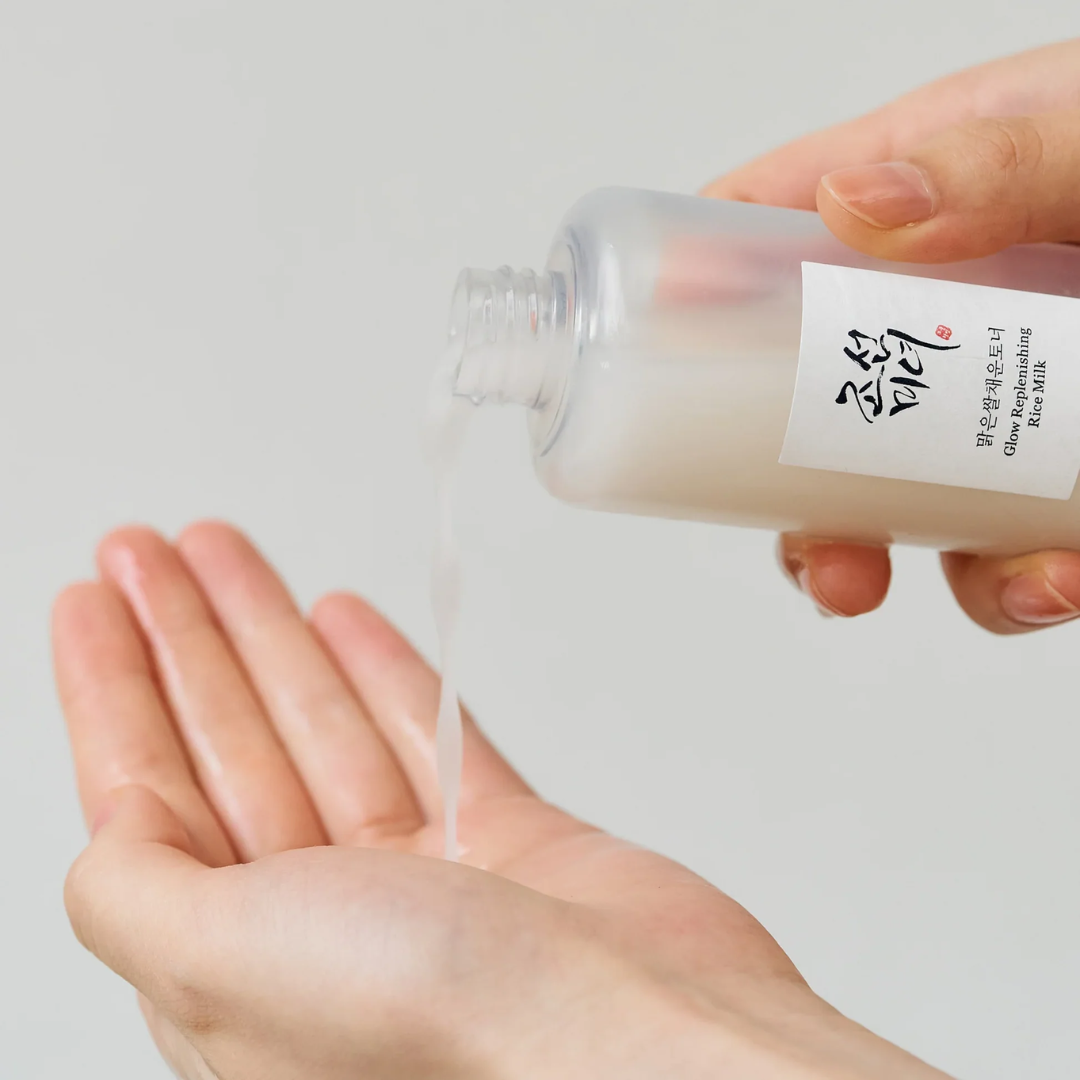 Hand holding a small container of toner with a white label against a light gray background