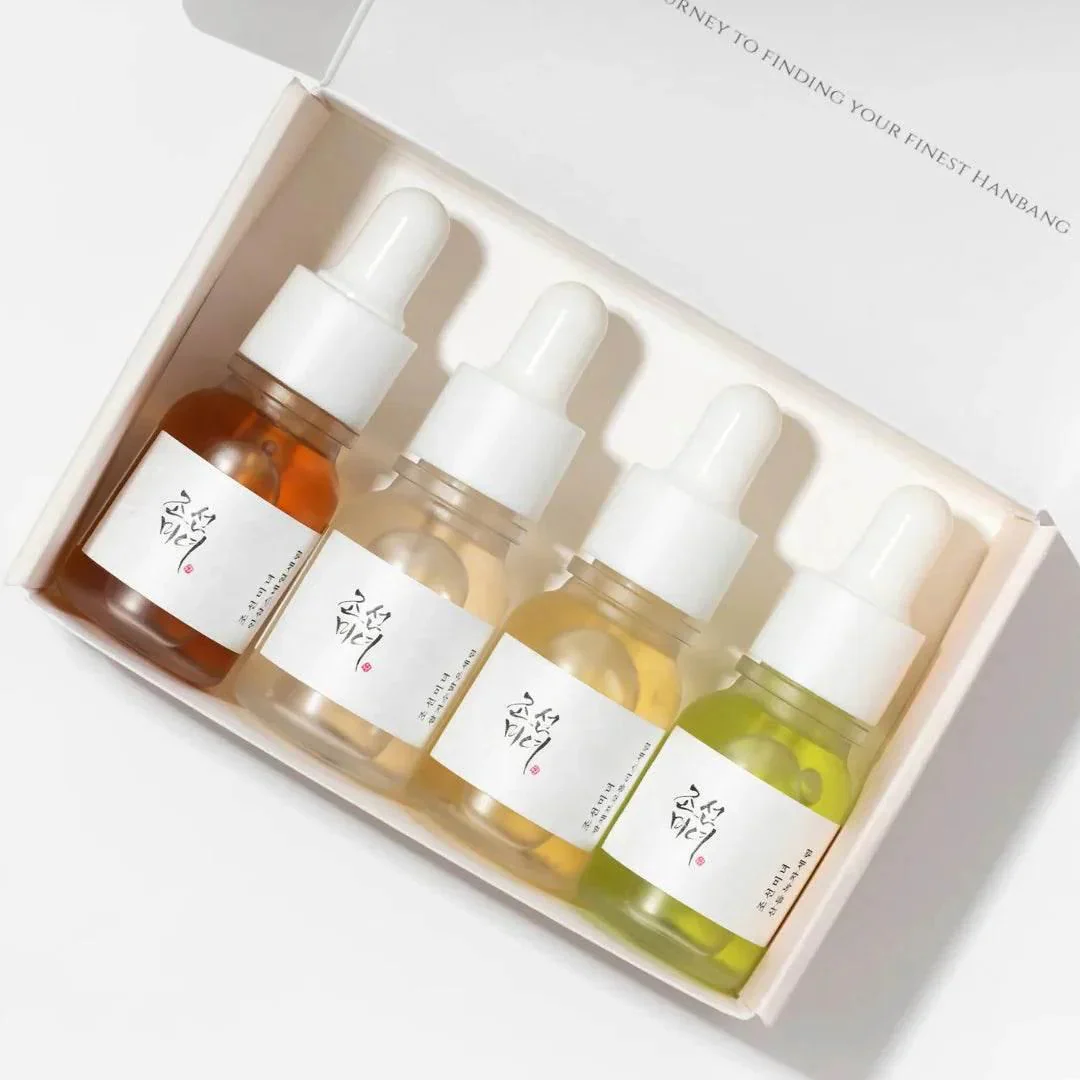 Four dropper bottles with different colored liquids in a box on a light gray background