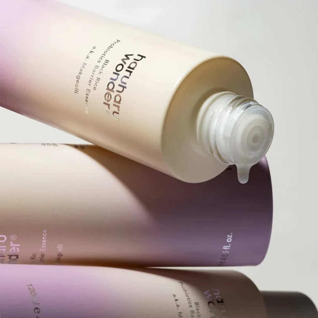 Three skincare bottles with a droplet of product on a light background