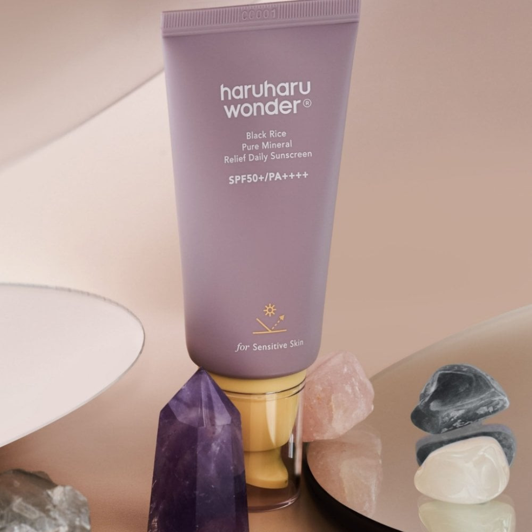 Purple sunscreen tube labeled 'haruharu wonder' on a neutral background with stones.