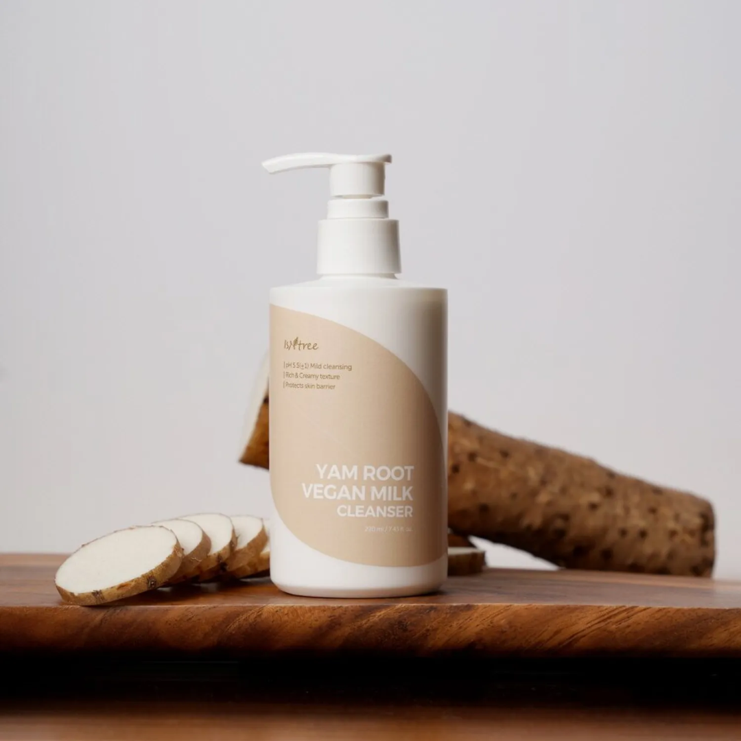 Yam root vegan milk cleanser bottle on a wooden surface with yam slices.