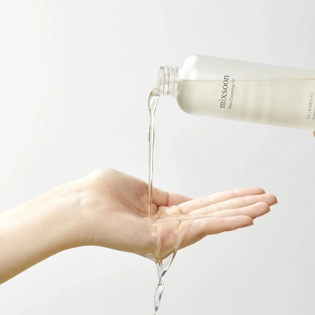 Hand pouring clear liquid from a bottle labeled 'mixsoon' onto a palm against a light background.