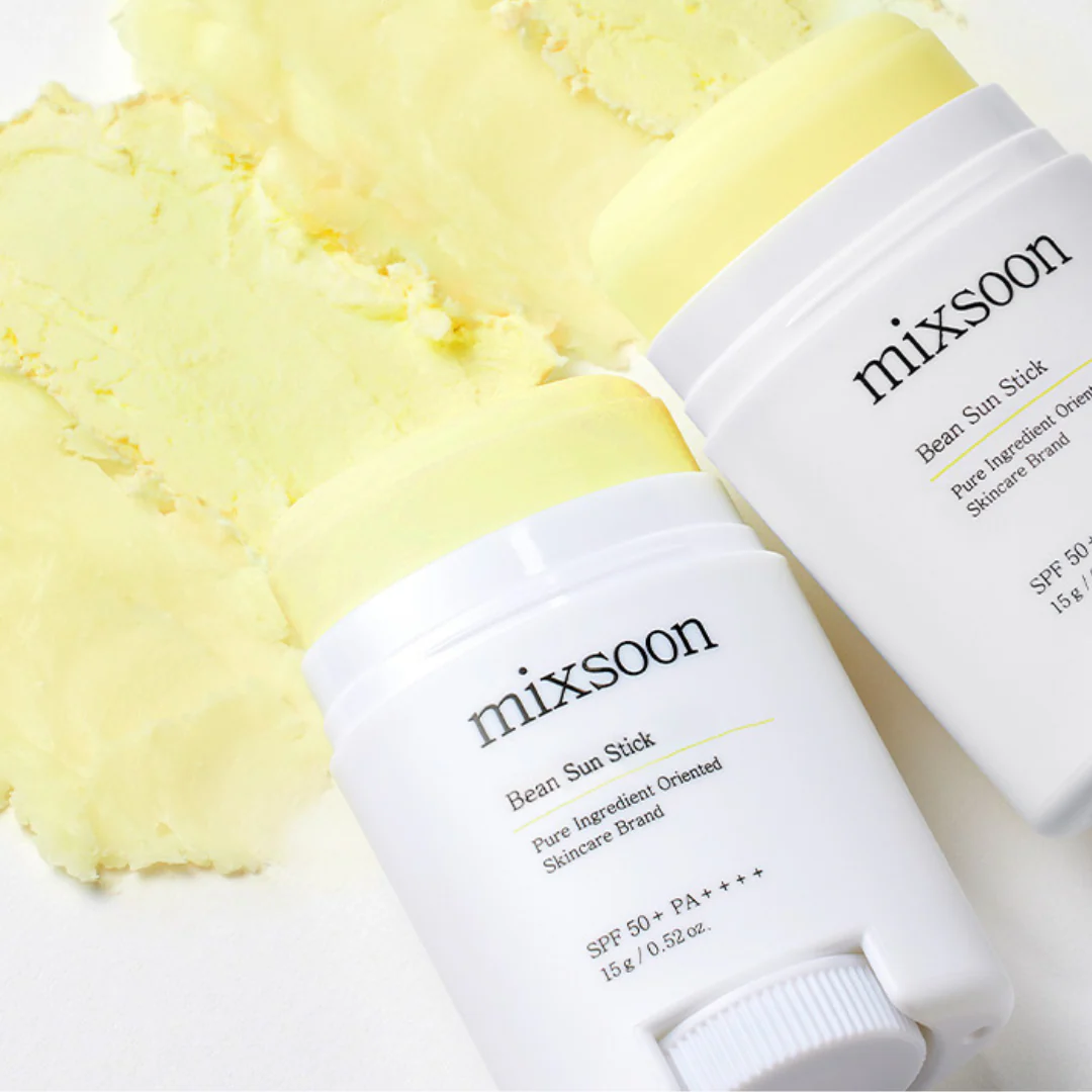 Two 'mixsoon' bean sun sticks with a smear of yellow cream on a white background
