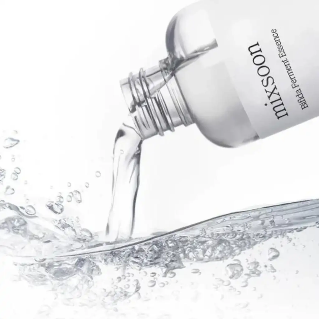Bottle of mixsoon essence being poured with water splashes on a white background