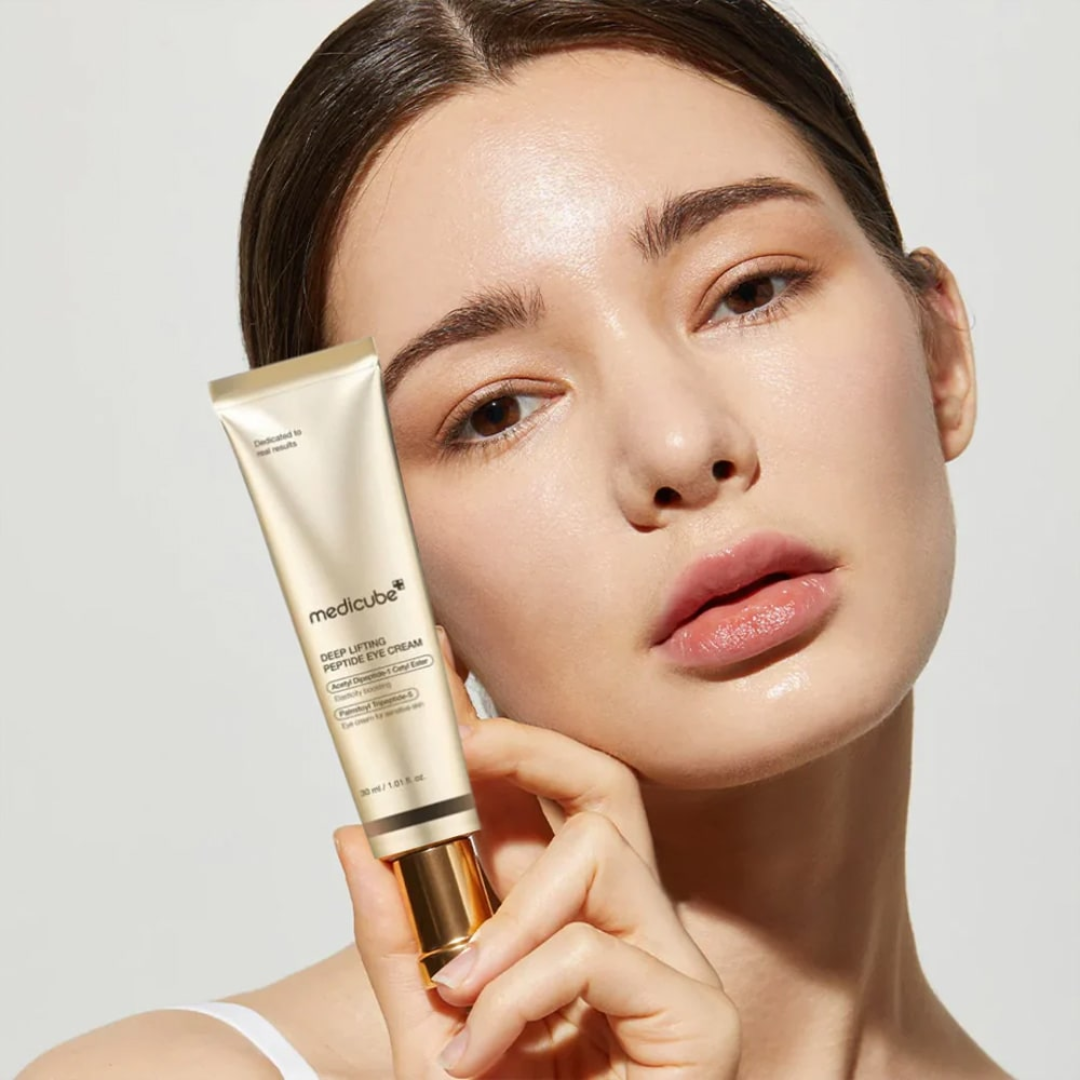 Woman holding a skincare product with a plain background