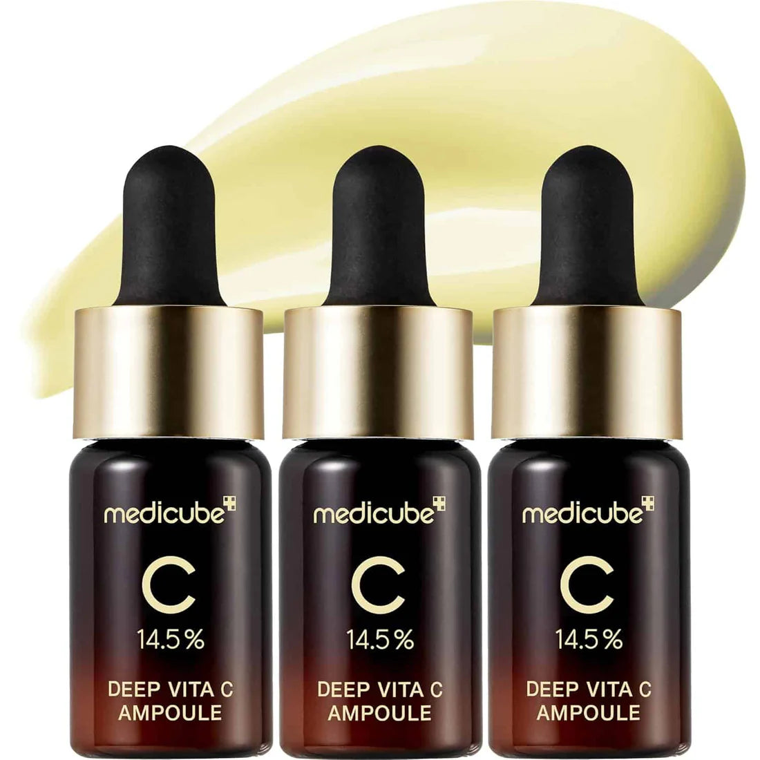 Three Medicube Deep Vita C Ampoules with a droplet of liquid above them on a white background.