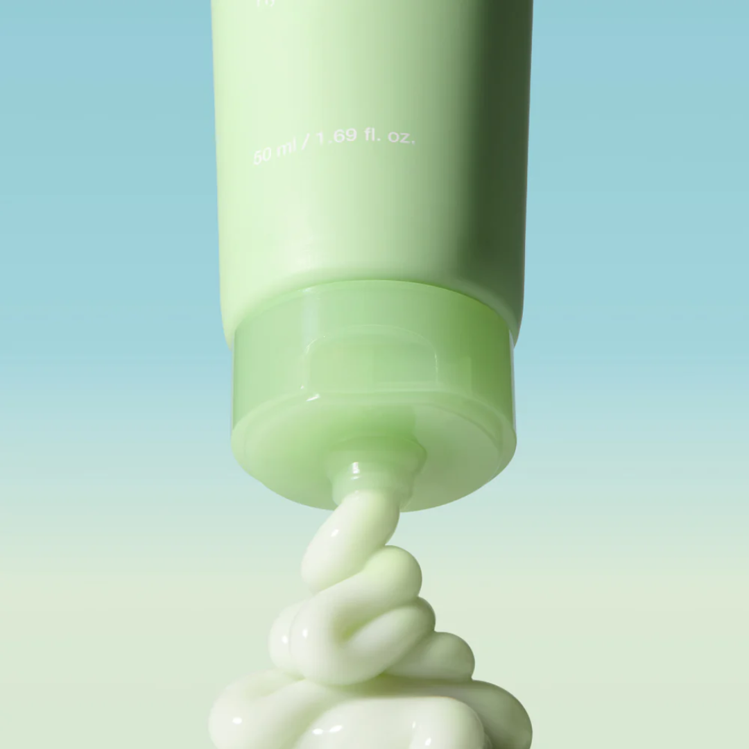 Green tube of cream with white cream being squeezed out on a gradient blue to green background