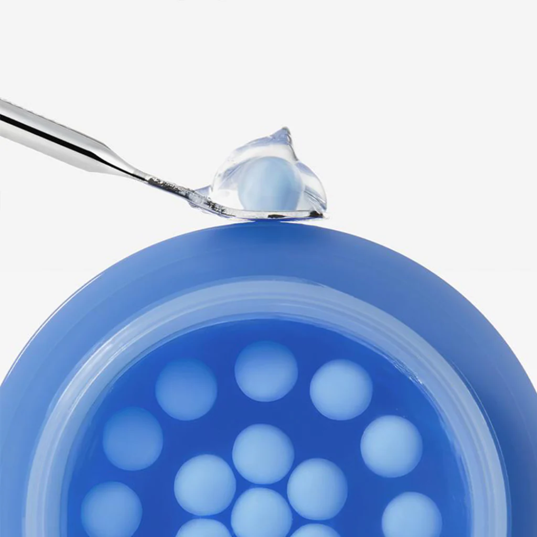 Blue silicone mold with a spoonful of blue substance on a white background