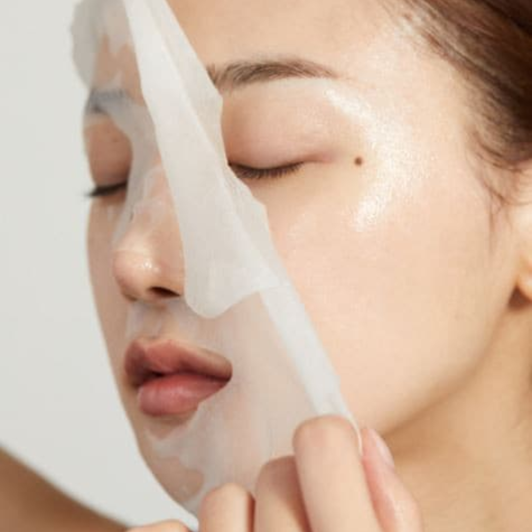 Person applying a white mask to their face with a neutral background