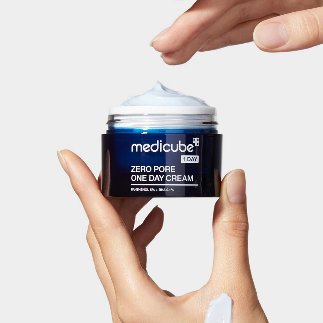 Hand holding a jar of Medicube Zero Pore One Day Cream against a light gray background