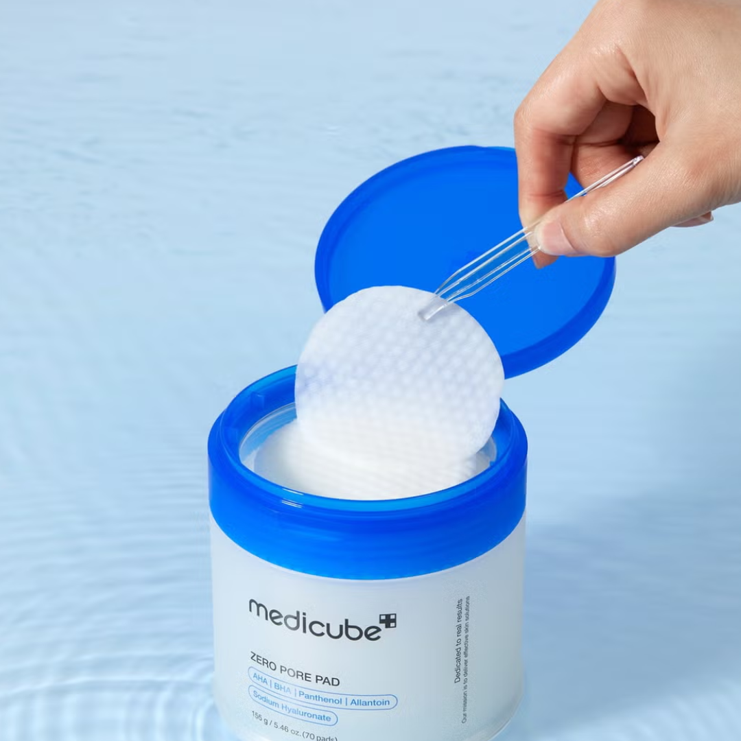 Hand taking a white pad from a Medicube container on a light blue background