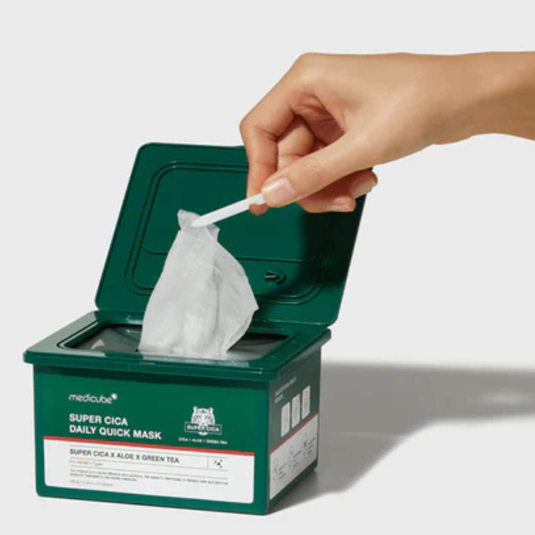 Hand taking a maskfrom a green box labeled 'Super Cica Daily Quick Mask' on a white background