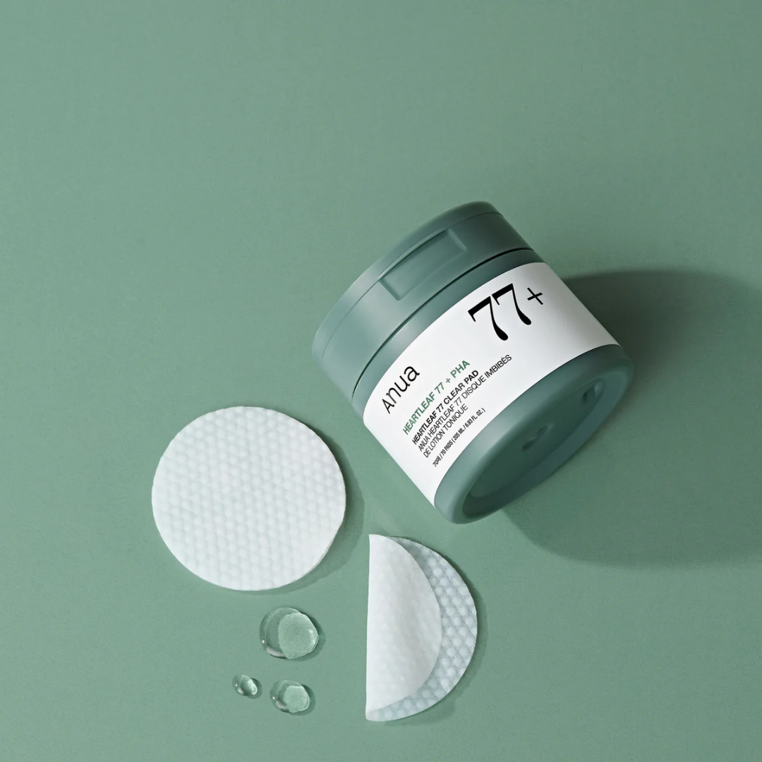 Cosmetic jar with a lid, cotton pads, and droplets on a green background