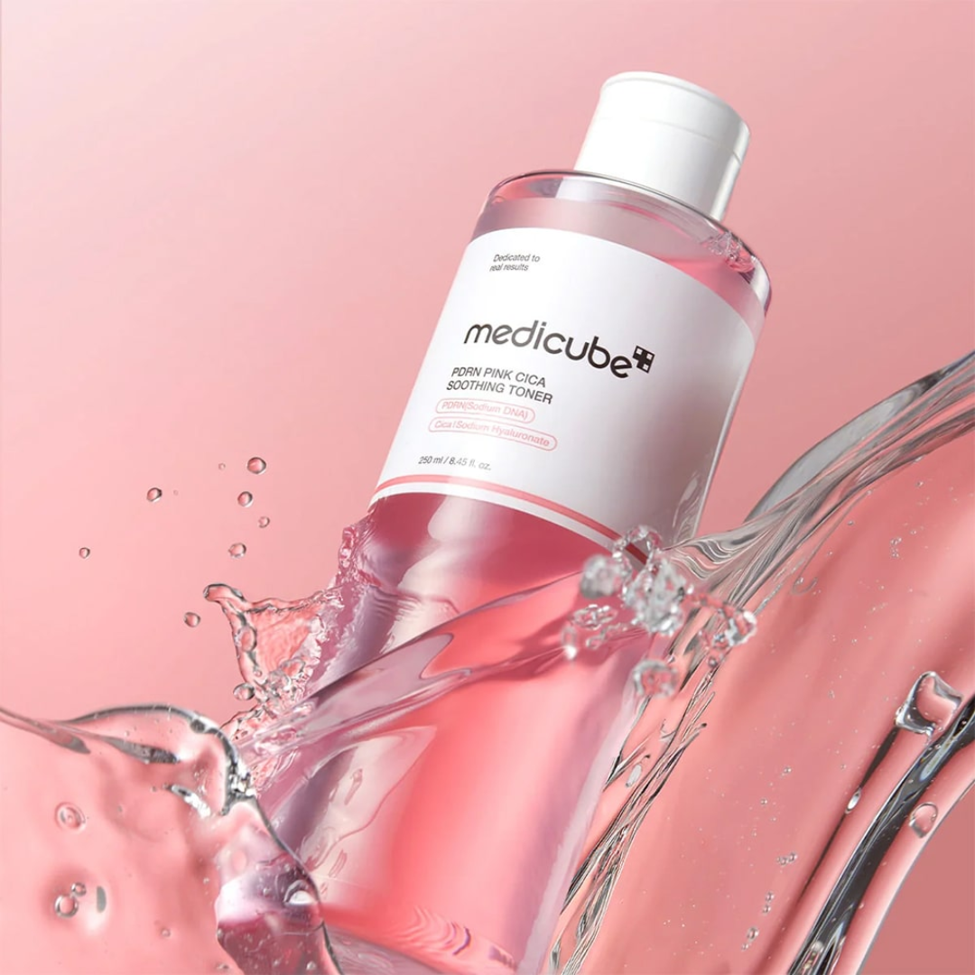 Medicube toner bottle with water splashes on a pink background