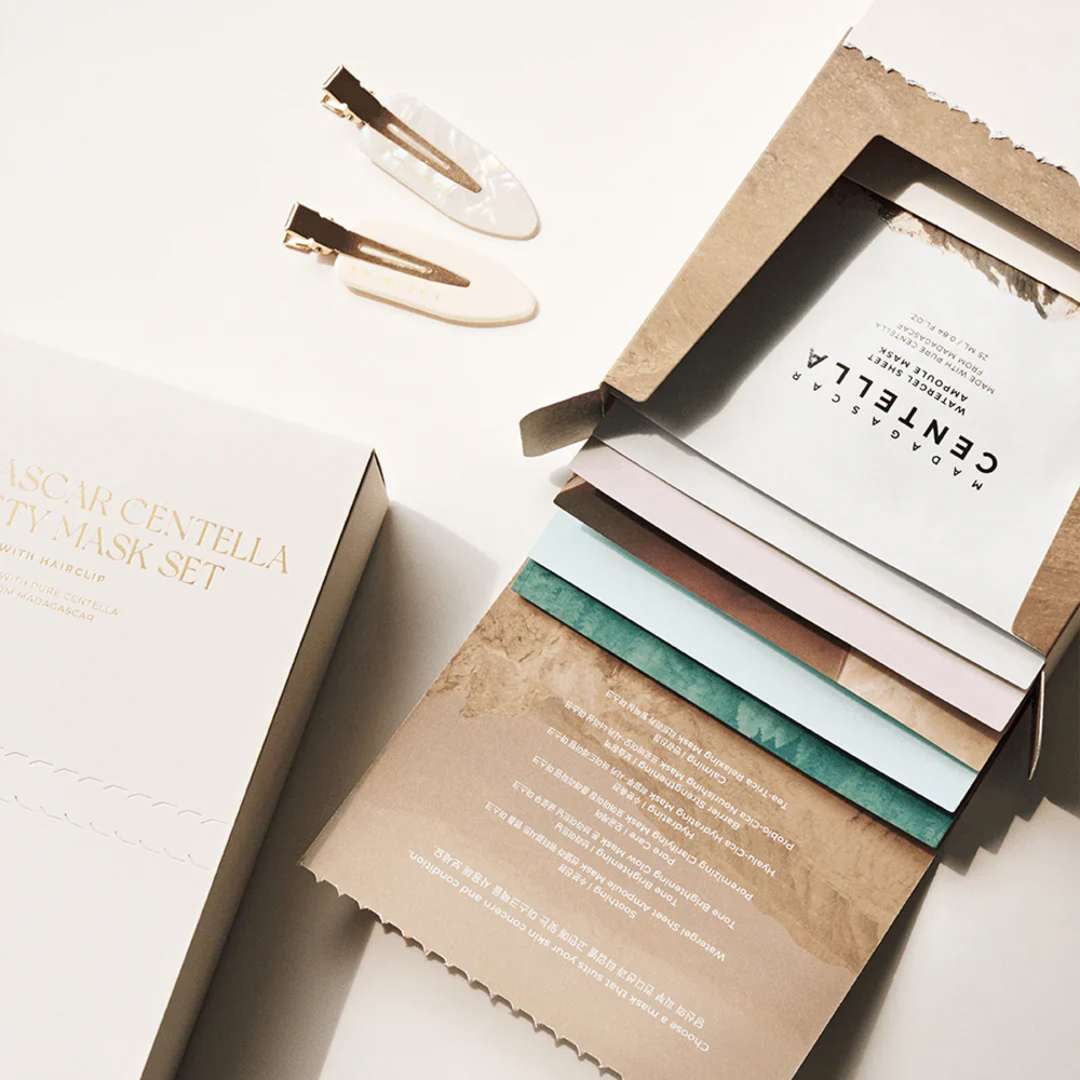 Set of facial masks with a box and hair clips on a light background
