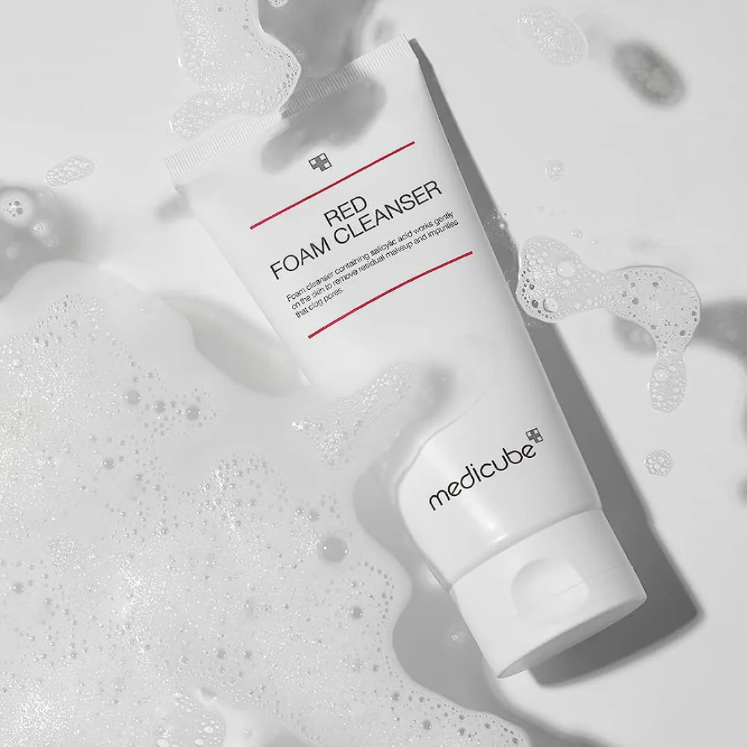 White foam cleanser bottle with 'Medicube' branding on a gray background with bubbles.