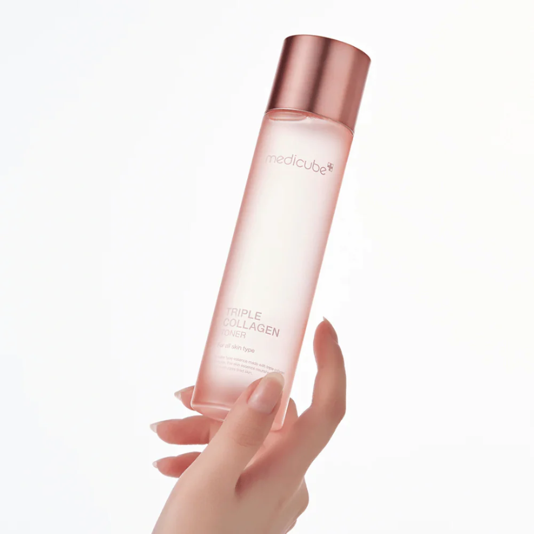 Hand holding a pink skincare bottle with 'Medicube' branding on a white background
