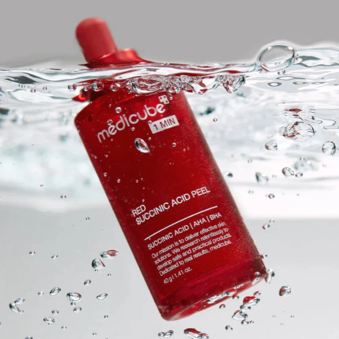 Red bottle labeled 'medicube' with water droplets and bubbles around it.