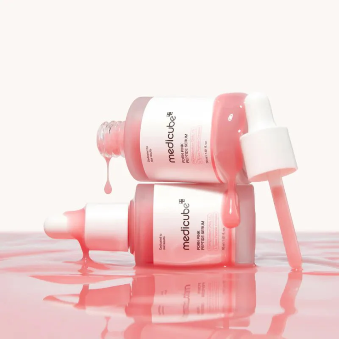 Two bottles of Medicube serum with pink liquid on a white background