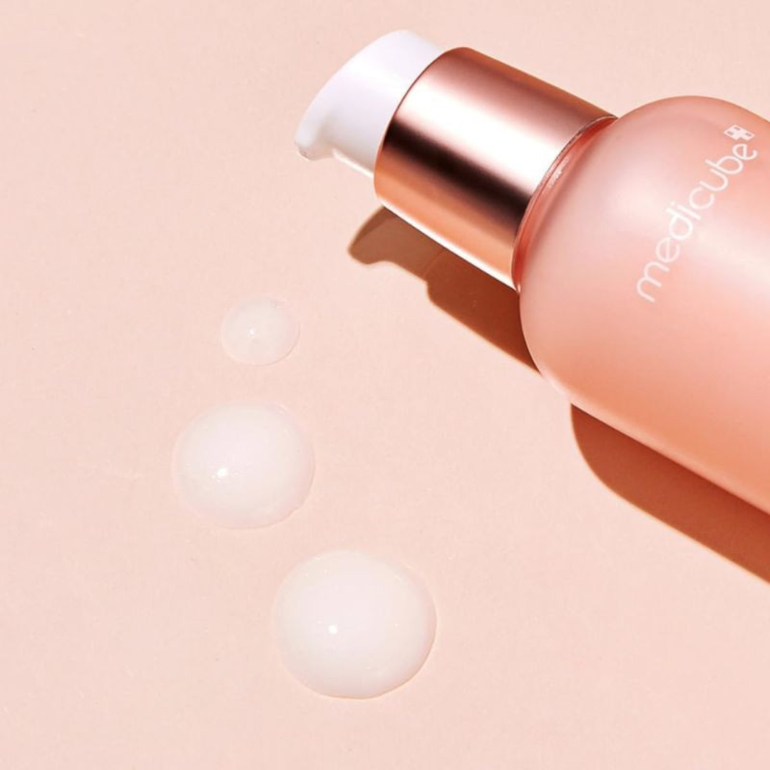 Cosmetic bottle with rose gold cap and pink body on a beige background