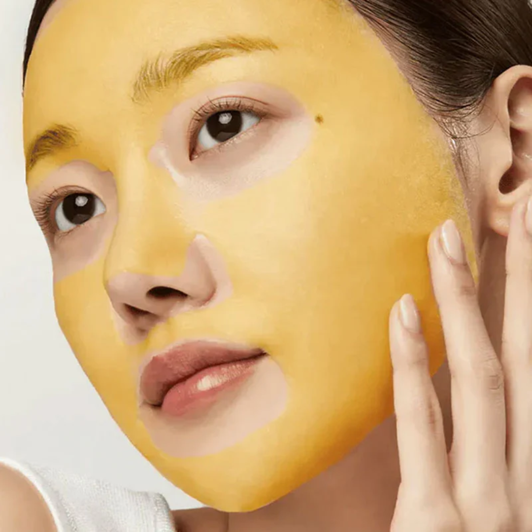 Woman wearing a yellow face mask with one hand on her face.